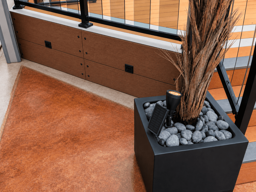 Composite deck corner with picture-frame border and LED railing base glowing at night