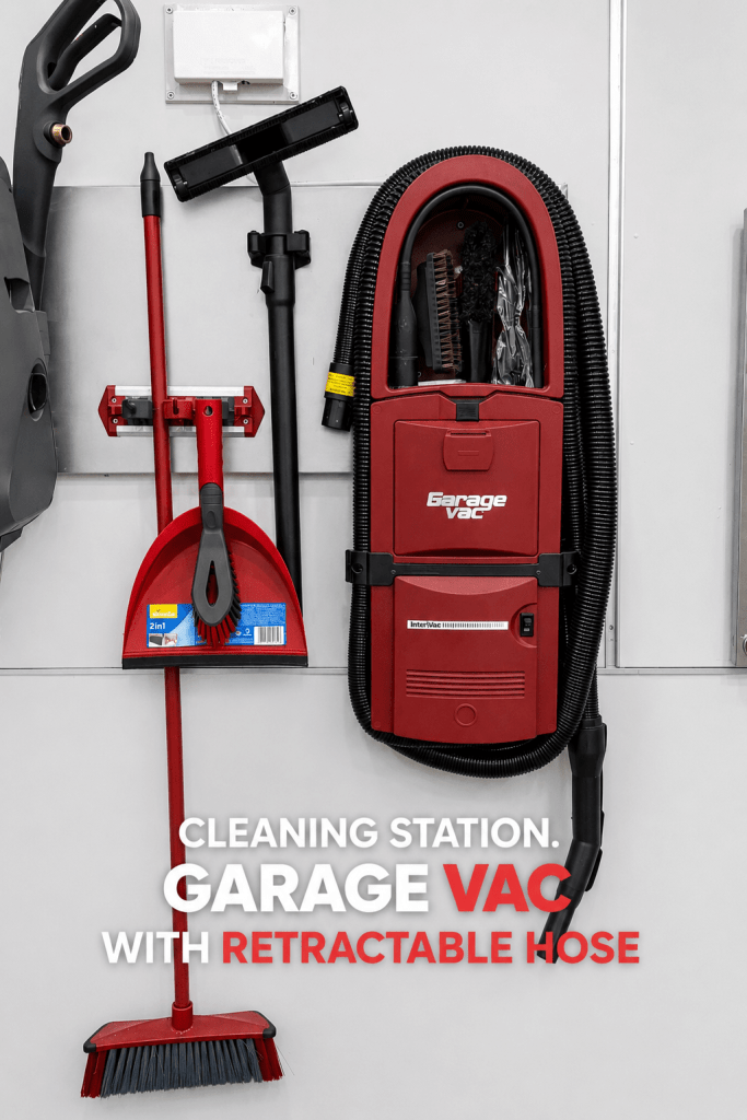 Wall-mounted cleaning station featuring a Garage Vac with a retractable hose, a broom, a dustpan, and various cleaning tools.